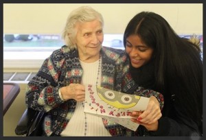 Rasheeda Ramsingh reading a holiday card with a woman in a senior home. Photo Credit: Fawzia Rahman