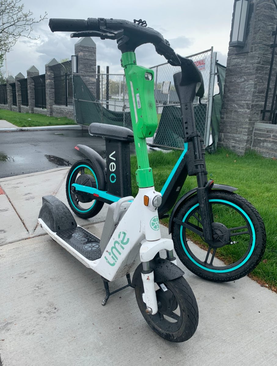 Lime and Veo Scooters parked by the sidewalk