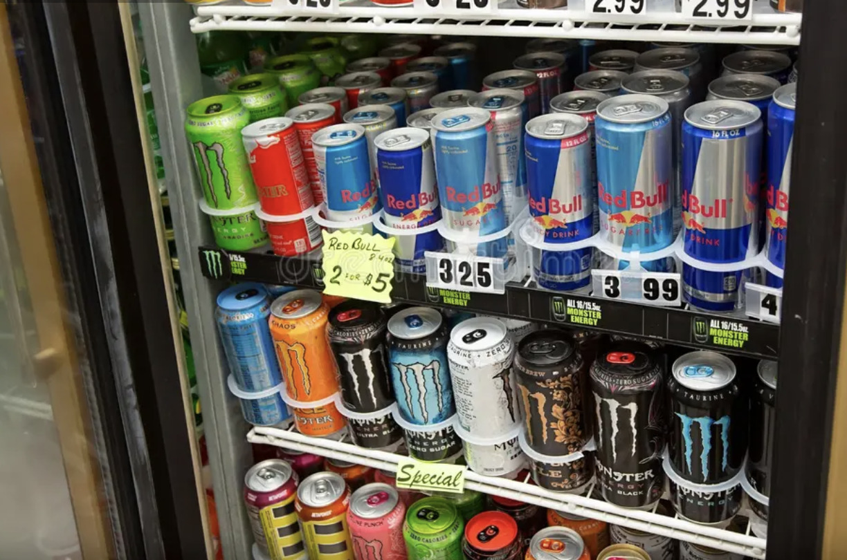A view inside a commercial beverage refrigerator, featuring a variety of popular energy drink brands