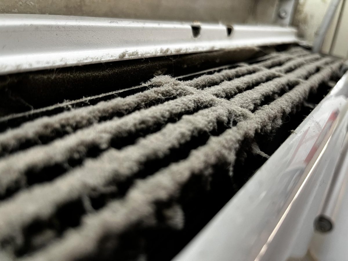 Close up image of AC unit in Room 121 filled with clots of dust in the AC’s vents.