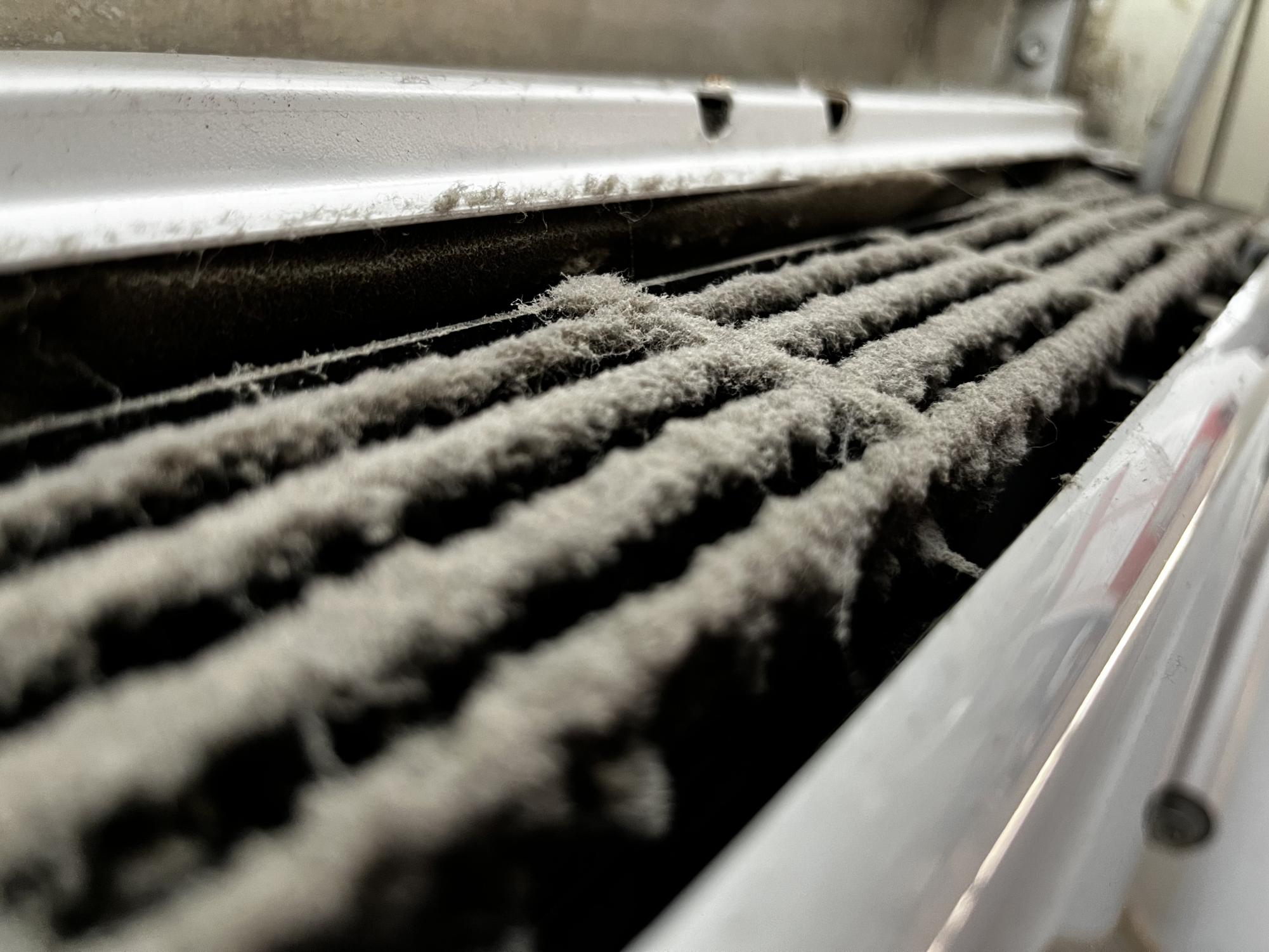 Close up image of AC unit in Room 121 filled with clots of dust in the AC’s vents.